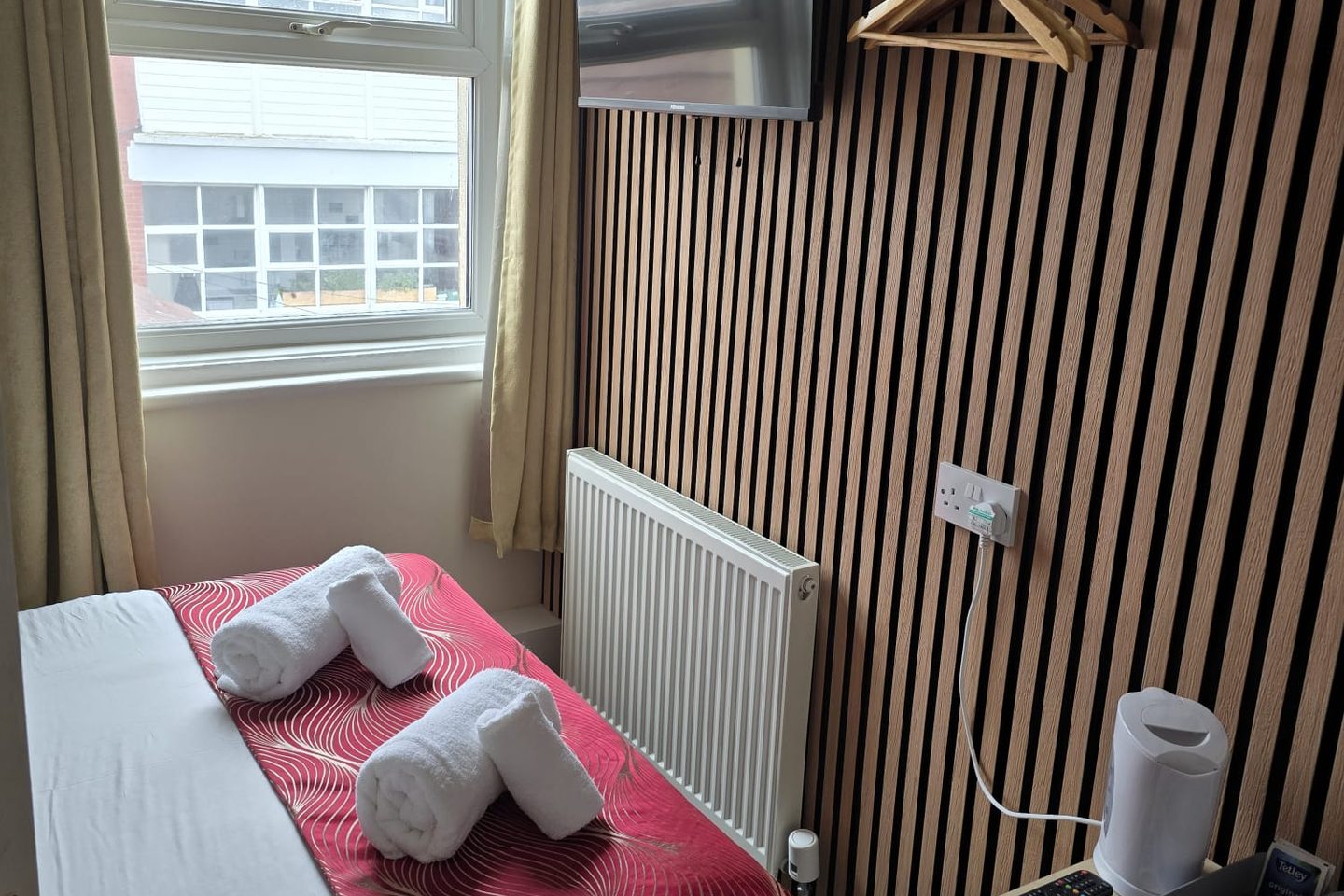 Small Double Room at The Cumbrian Hotel, Blackpool, with an oak slat wall, wall-mounted TV and a window